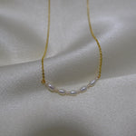 CAELLIA freshwater pearl necklace with small rice-shaped pearls on a delicate gold chain.