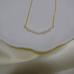 CAELLIA freshwater pearl bead necklace with a delicate gold chain on a white dish.