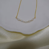 CAELLIA freshwater pearl bead necklace with a delicate gold chain on a white dish.