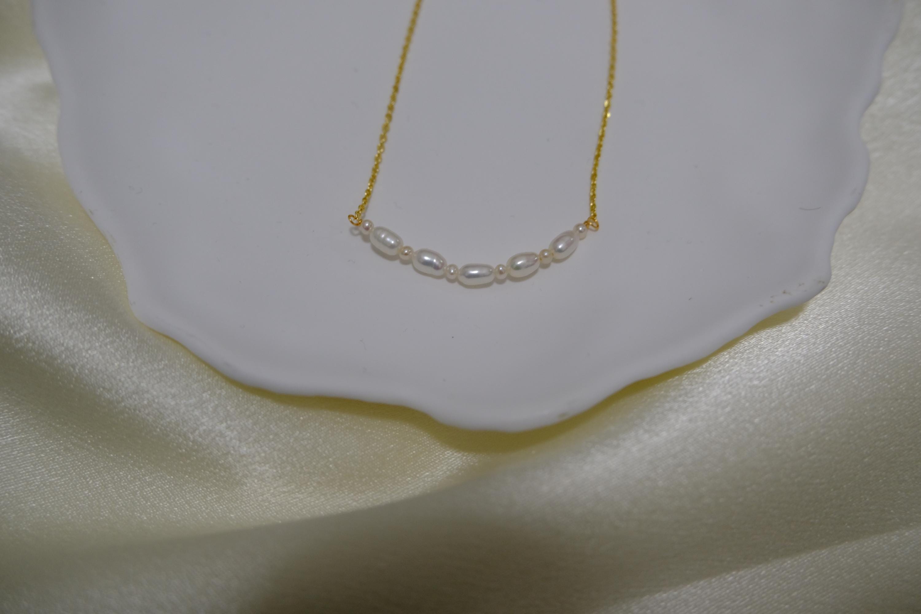 CAELLIA freshwater pearl bead necklace with a delicate gold chain on a white dish.