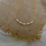 CAELLIA freshwater pearl bead necklace featuring a delicate gold chain on a burlap background.