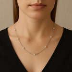 A woman wearing a Caellia sterling silver necklace featuring spaced freshwater pearls.