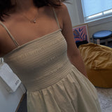 A person wears a dainty CAELLIA freshwater pearl pendant necklace with a bow detail.