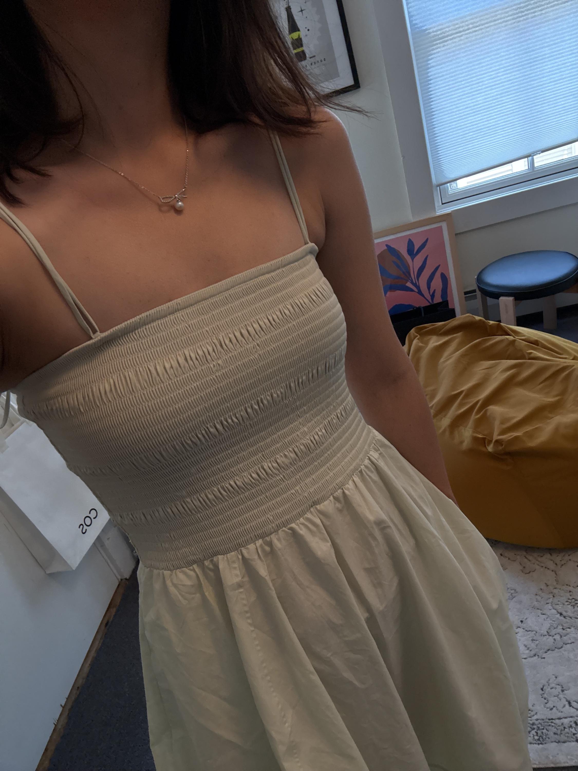 A person wears a dainty CAELLIA freshwater pearl pendant necklace with a bow detail.