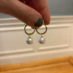 Caellia 18K gold hoop earrings featuring a single dangling freshwater pearl.