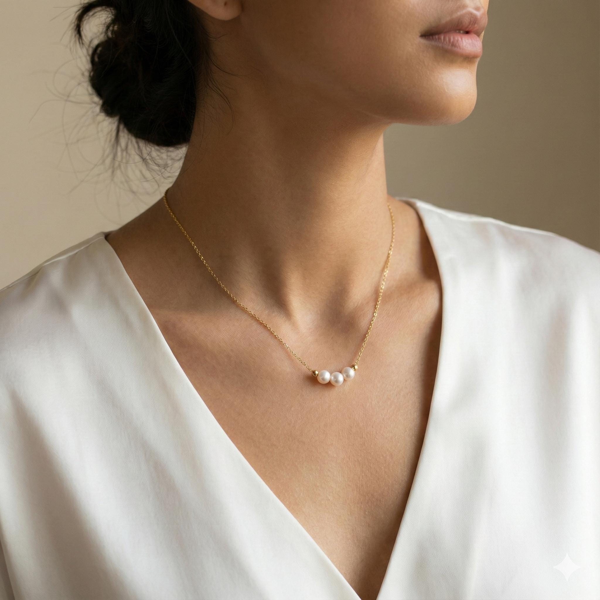 A model wears a Caellia 18k gold dainty choker necklace featuring three small freshwater pearls.