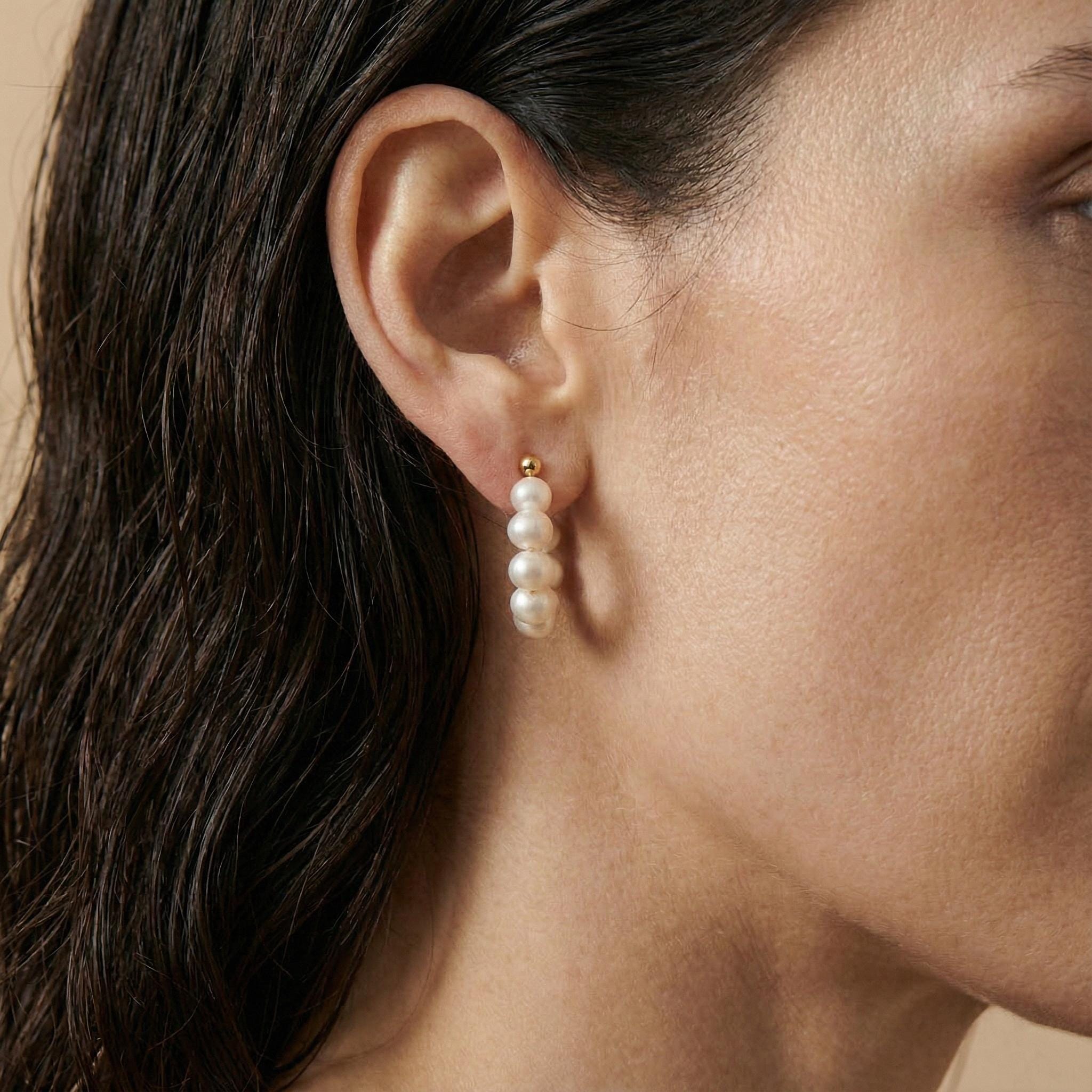 A model wears a Caellia 18K gold hoop earring featuring a row of four small freshwater pearls.