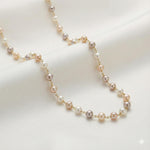 Caellia freshwater pearl station necklace featuring champagne, grey, and white pearls on a gold chain.