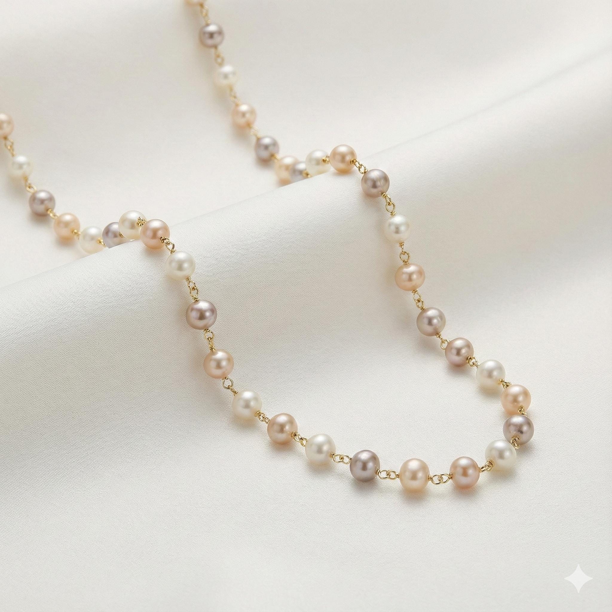 Caellia freshwater pearl station necklace featuring champagne, grey, and white pearls on a gold chain.