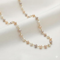 Caellia freshwater pearl station necklace featuring champagne, grey, and white pearls on a gold chain.