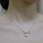 A CAELLIA dainty freshwater pearl pendant necklace featuring a sparkling bow design.