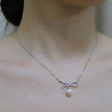 A CAELLIA dainty freshwater pearl pendant necklace featuring a sparkling bow design.