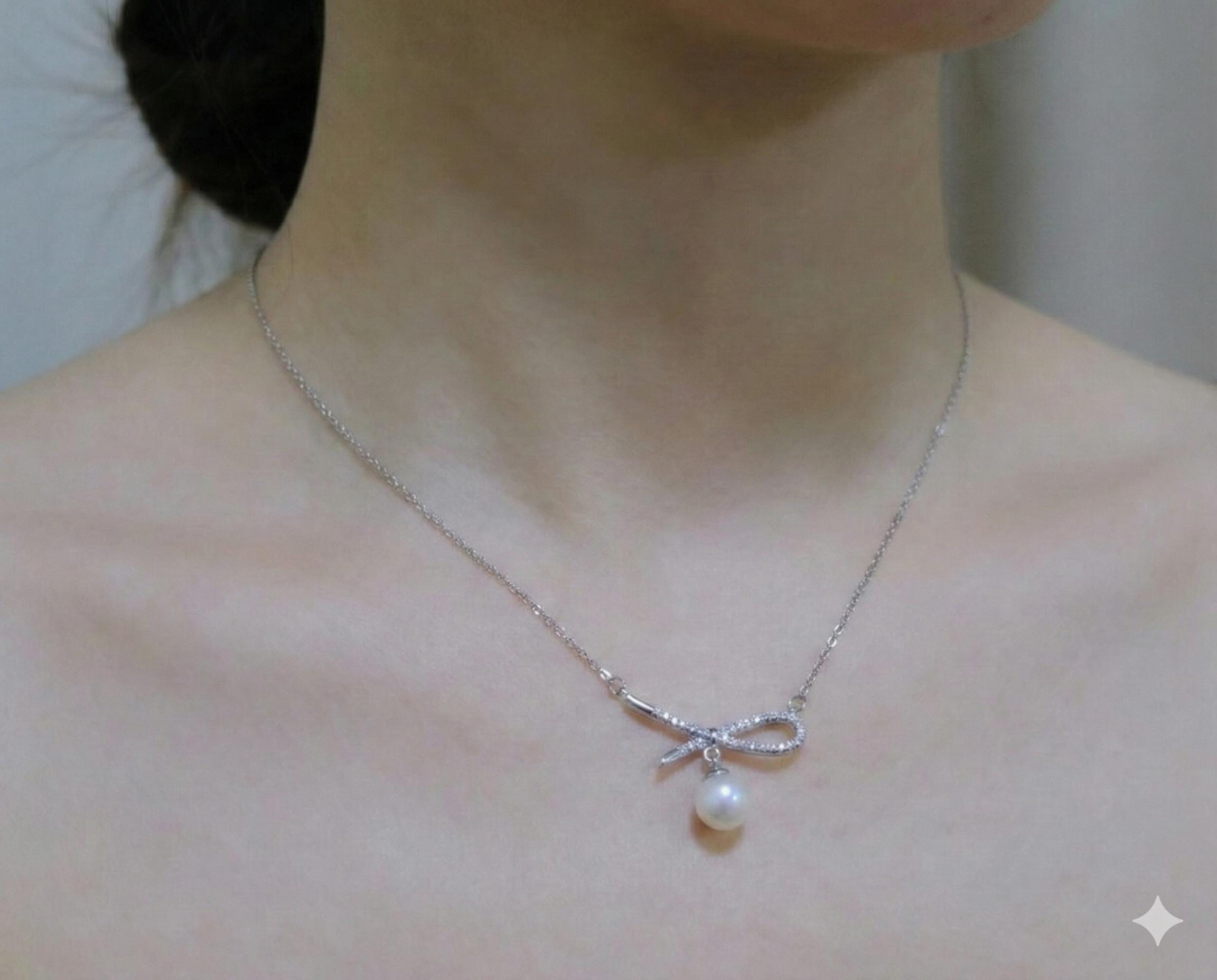A CAELLIA dainty freshwater pearl pendant necklace featuring a sparkling bow design.