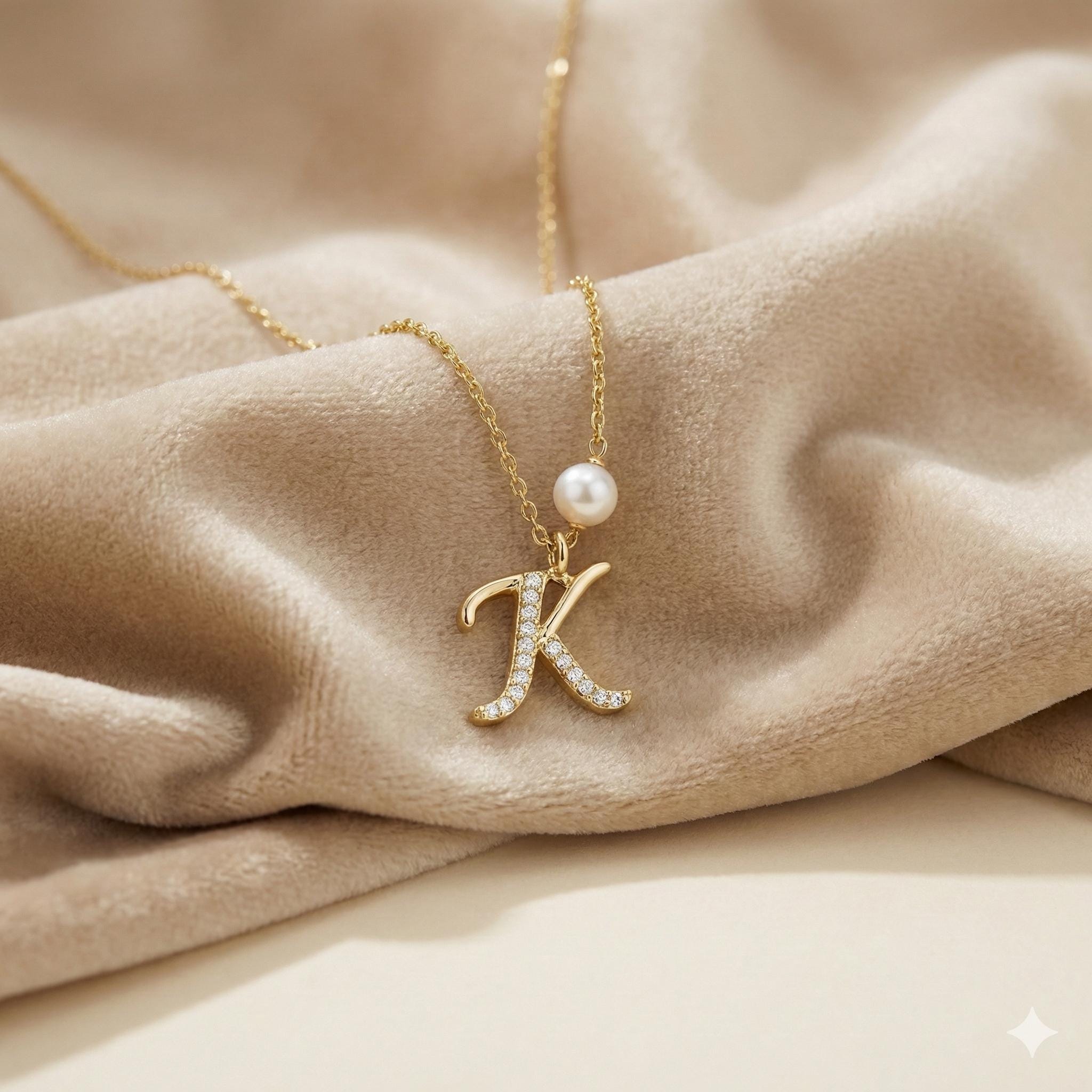 CAELLIA gold necklace featuring a pavé letter K pendant and a single pearl on a delicate chain.