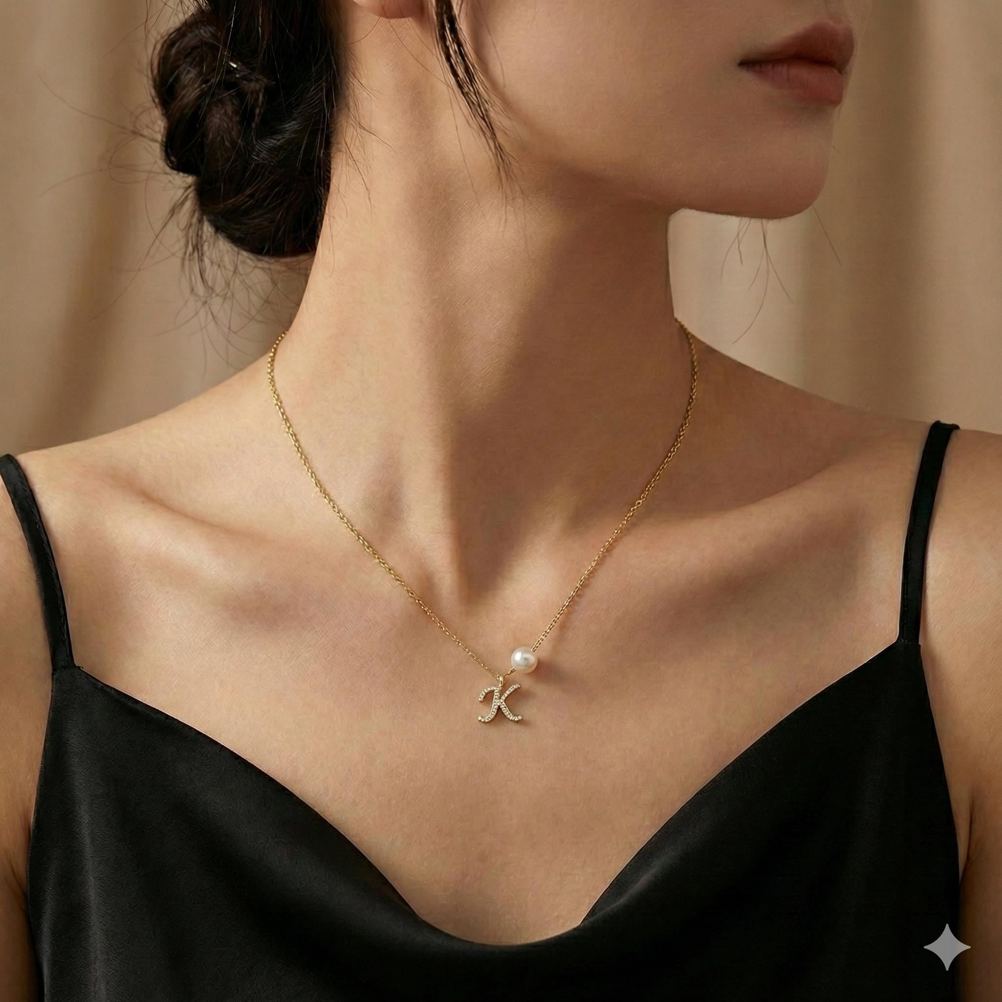 A gold chain necklace by CAELLIA featuring a pavé letter K pendant and a single pearl accent.