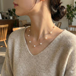 A woman wears a Caellia 14K gold dainty freshwater pearl necklace with evenly spaced pearls.