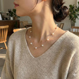 A woman wears a Caellia 14K gold dainty freshwater pearl necklace with evenly spaced pearls.