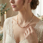 A woman wears a Caellia freshwater pearl station necklace in champagne and grey on a gold chain.