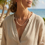 A woman wears a Caellia freshwater pearl station necklace with champagne and grey pearls on gold.