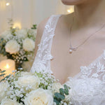 A bride wears a dainty CAELLIA freshwater pearl pendant necklace with a delicate bow design.