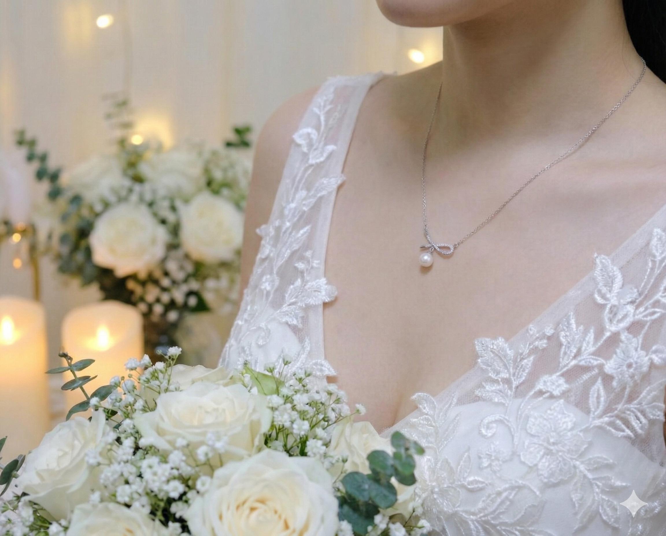 A bride wears a dainty CAELLIA freshwater pearl pendant necklace with a delicate bow design.