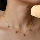 A dainty CAELLIA necklace featuring five lavender teardrop freshwater pearls on a gold chain.