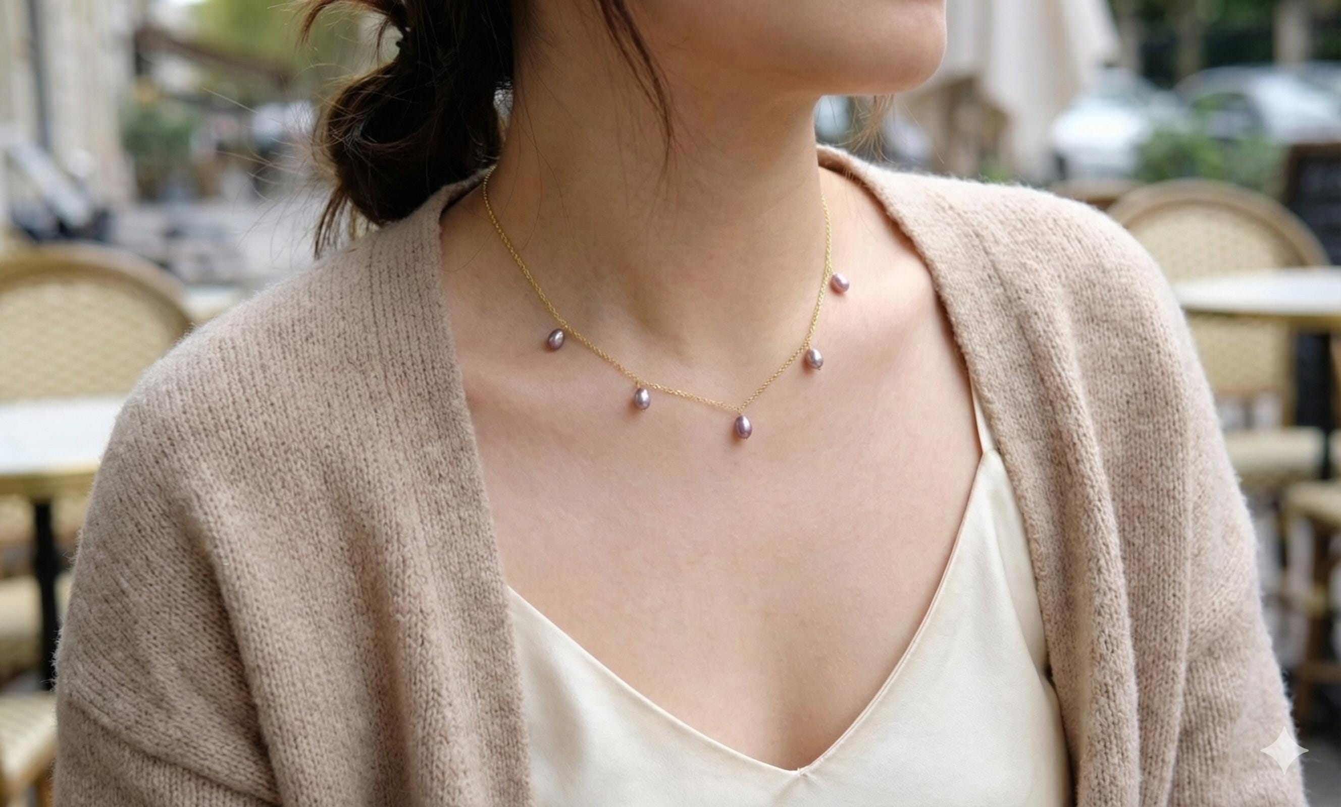 A woman wears a CAELLIA dainty lavender freshwater pearl choker on a 14K gold plated chain.