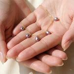 A dainty CAELLIA lavender freshwater pearl choker on a 14K gold plated chain held in two hands.