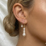 Caellia 14K gold hoop earrings featuring a single pearl and a cascading baroque pearl dangle.