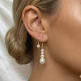 Caellia 14K gold hoop earrings featuring a single pearl and a cascading baroque pearl dangle.