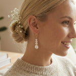 A woman wearing Caellia 14K gold hoop earrings with three dangling baroque freshwater pearls.