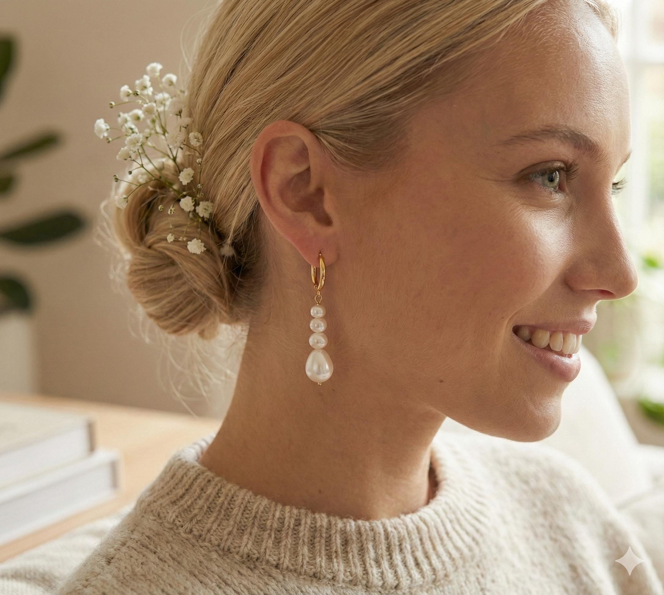 A woman wearing Caellia 14K gold hoop earrings with three dangling baroque freshwater pearls.