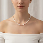 A woman wears a Caellia 14K gold and freshwater pearl choker necklace.