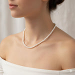 A woman wearing a Caellia 14K gold and freshwater pearl choker necklace.