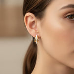 A woman wears Caellia 14K gold filled hoop earrings featuring a row of small freshwater pearls.