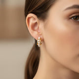 A woman wears Caellia 14K gold filled hoop earrings featuring a row of small freshwater pearls.