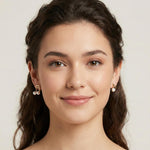 A woman wears Caellia 14K gold music note asymmetrical earrings featuring freshwater pearls.