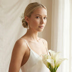 A bride wearing Caellia 14K gold hoop earrings with dangling baroque freshwater pearls.