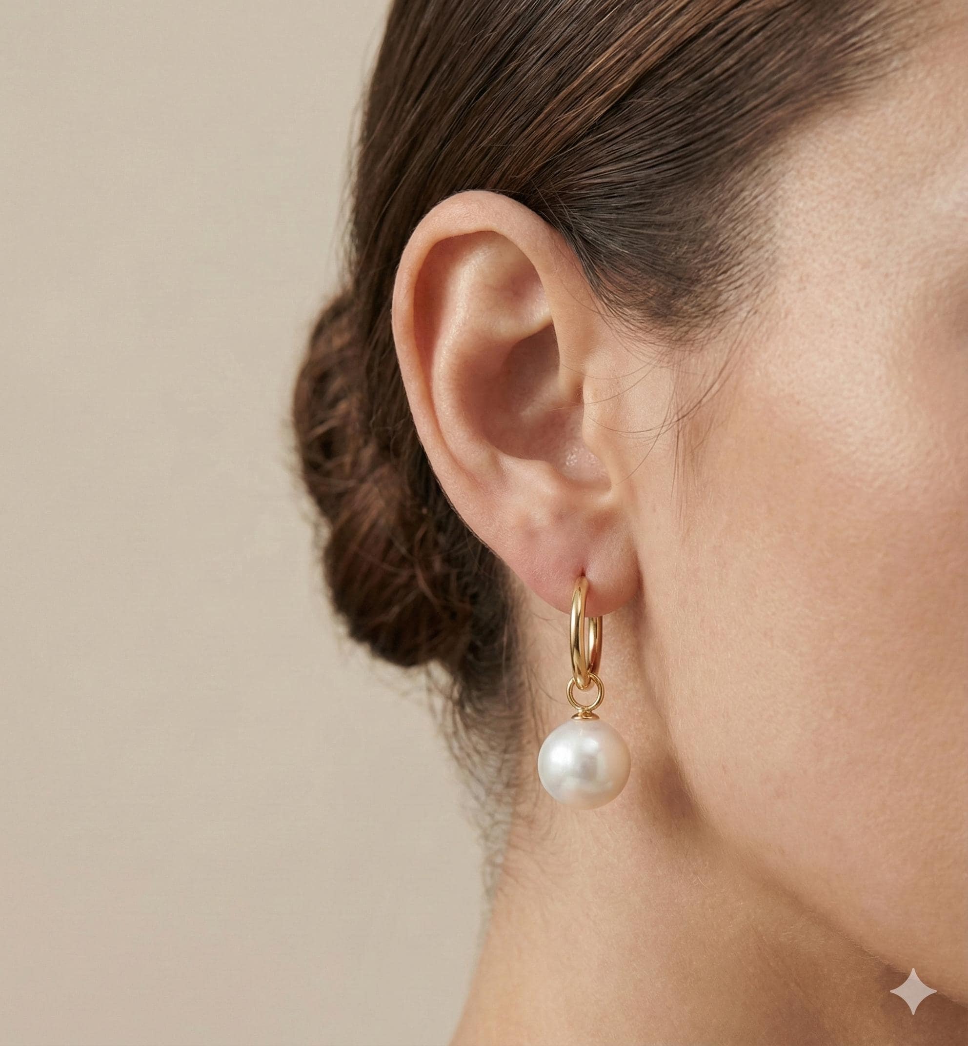 A model wears Caellia 18K gold hoop earrings featuring a dangling freshwater pearl.