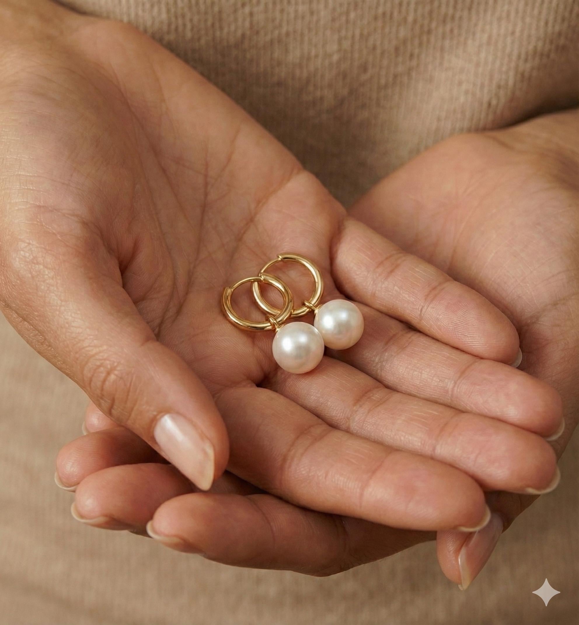 A pair of Caellia 18K gold hoop earrings featuring lustrous freshwater pearls held in cupped hands.