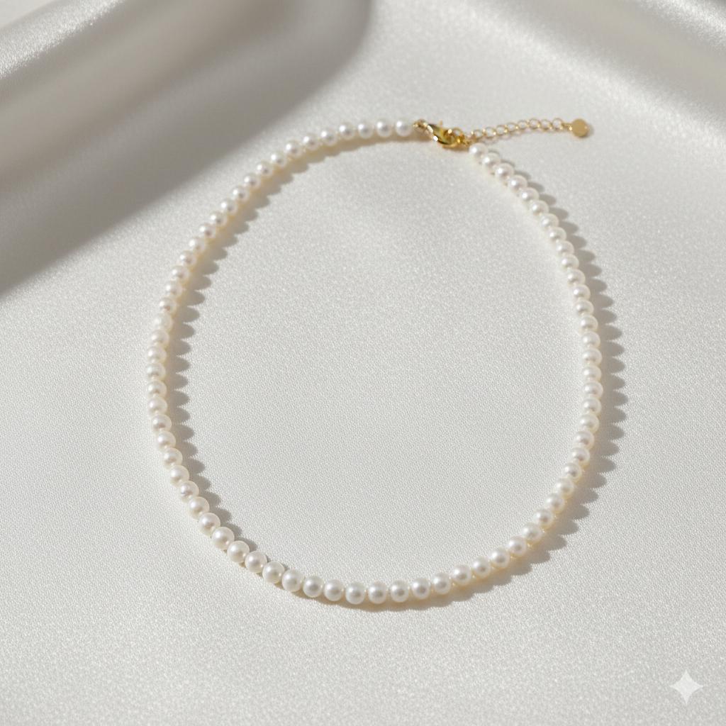 Caellia 14K gold and freshwater pearl choker necklace on a white silk background.