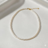 Caellia 14K gold and freshwater pearl choker necklace on a white silk background.