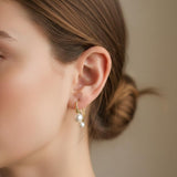 A model wears Caellia 18K gold plated freshwater pearl drop earrings on her ear.