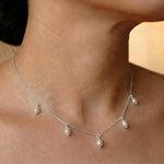A CAELLIA dainty silver-toned chain necklace featuring five small, dangling freshwater pearls.