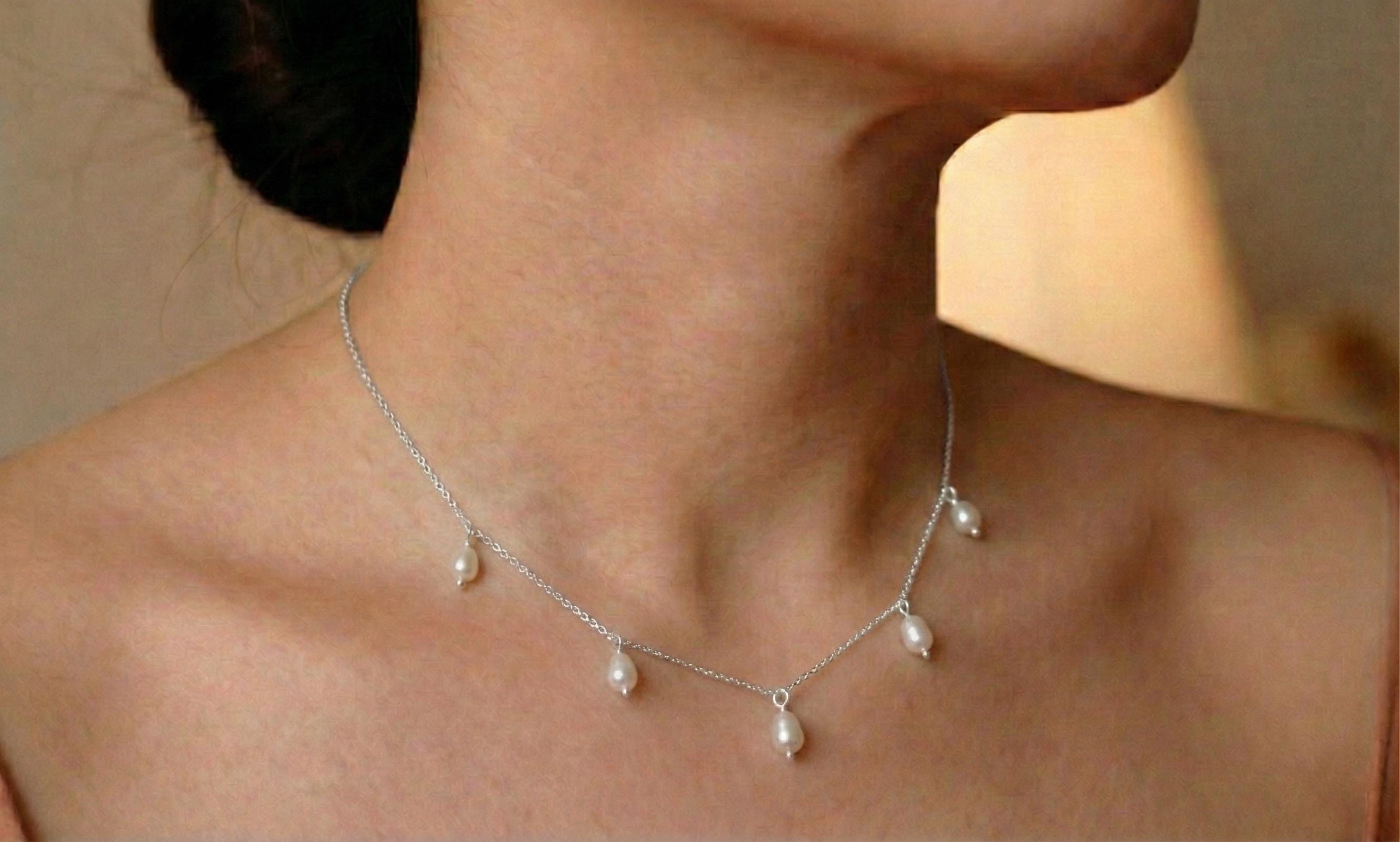 A CAELLIA dainty silver-toned chain necklace featuring five small, dangling freshwater pearls.