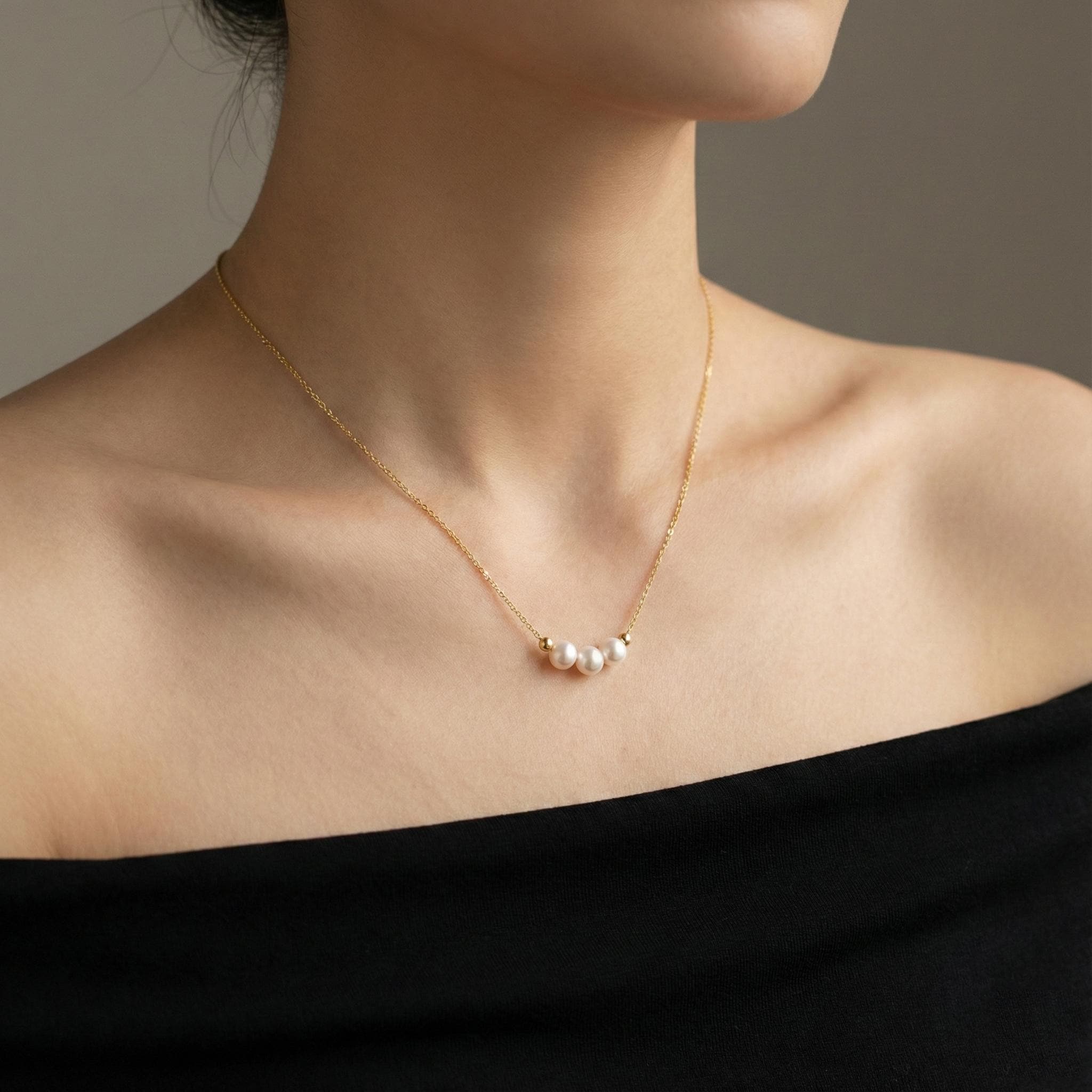 A model wears a Caellia dainty 18k gold choker necklace featuring three small freshwater pearls.
