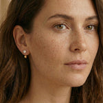 A model wears Caellia 14K gold double-sided stud earrings featuring a freshwater pearl.