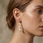 A model wears Caellia 14K gold triple freshwater pearl drop earrings.