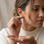 A woman wearing Caellia 14K gold triple freshwater pearl drop earrings.