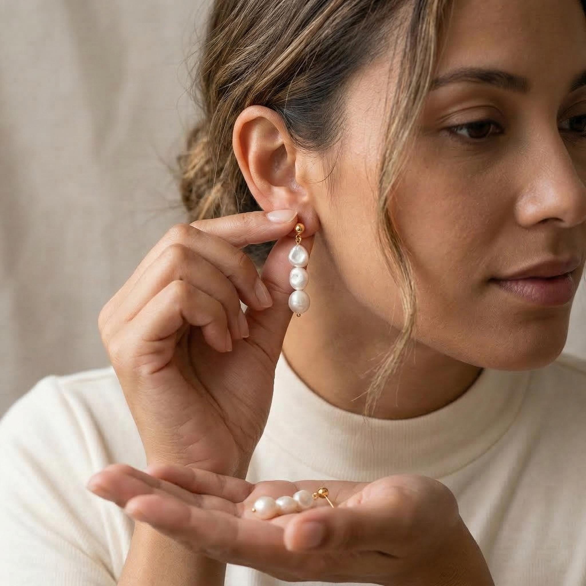 A woman wearing Caellia 14K gold triple freshwater pearl drop earrings.